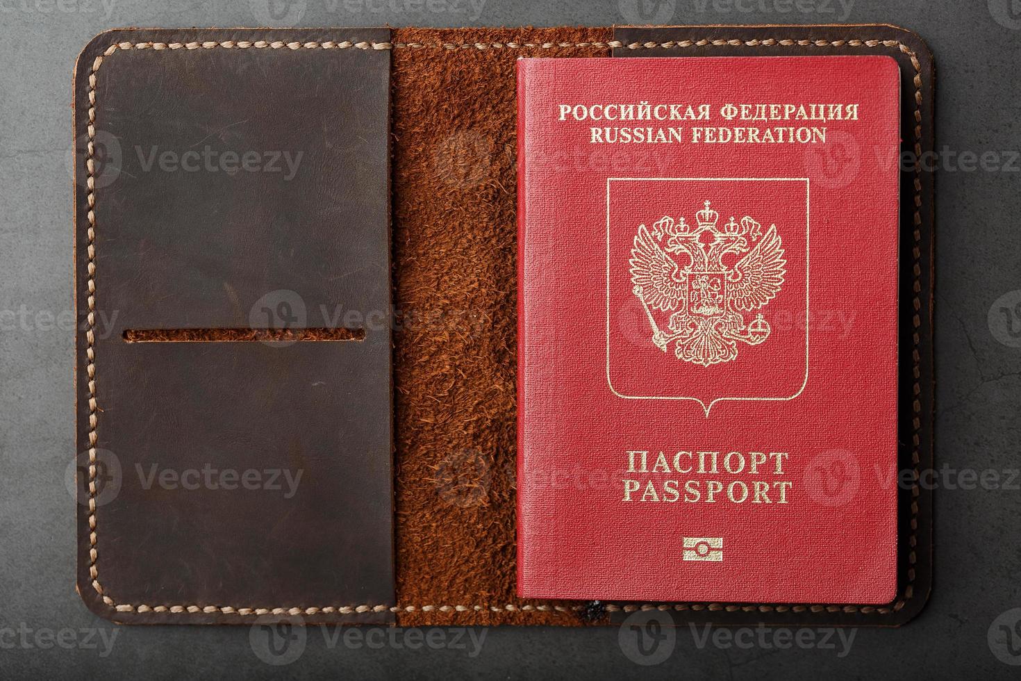 Brown leather cover with a red passport on a dark background photo