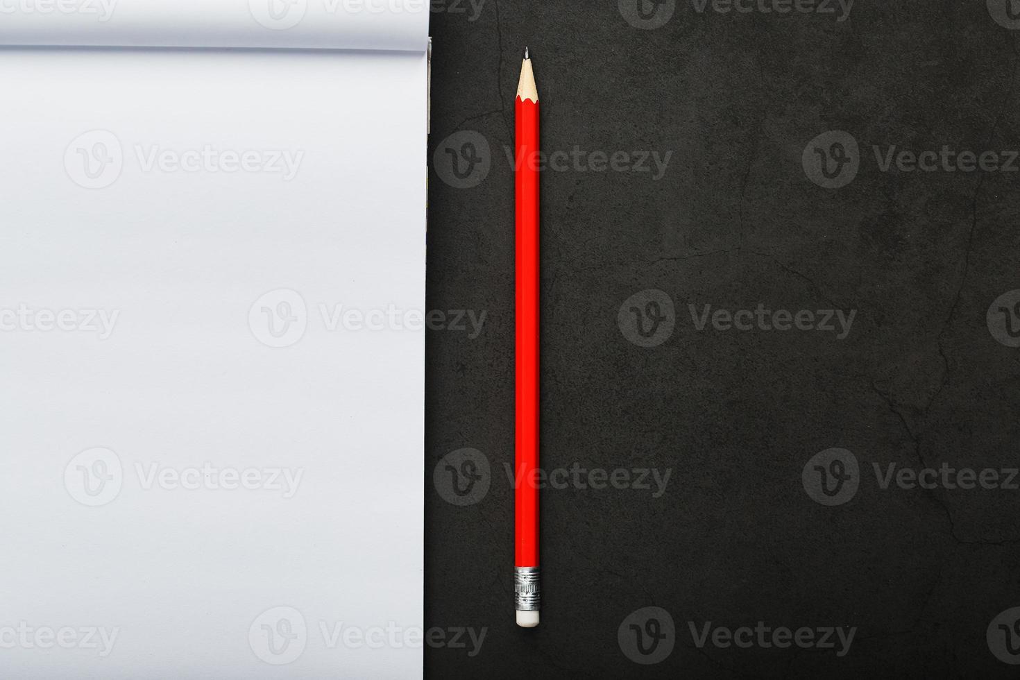 Notepad with a red pencil on a black stone plate background, for education, recording goals and deeds photo