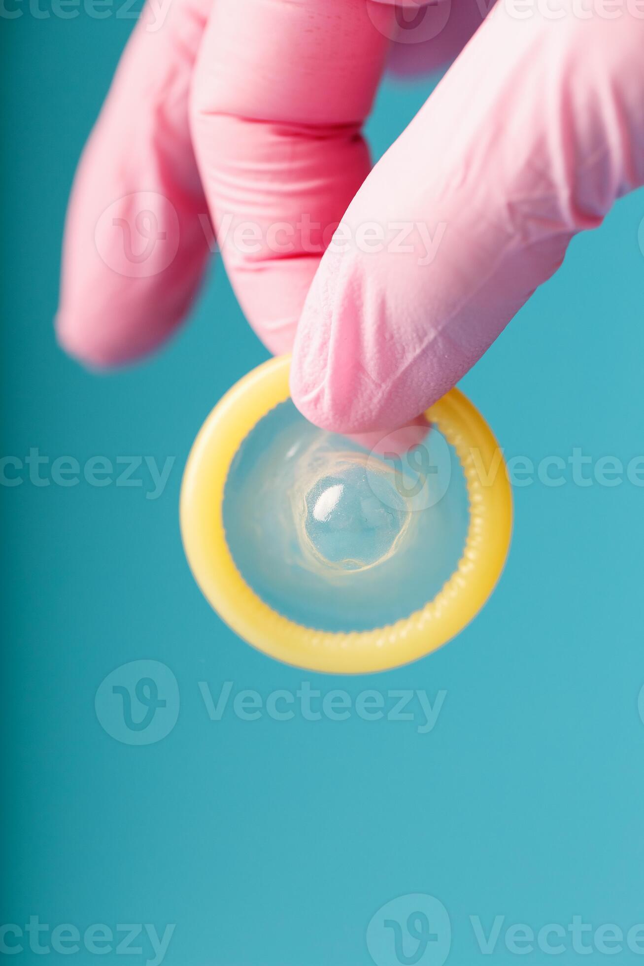 Condom contraception A hand in a pink glove holds a condom on a blue