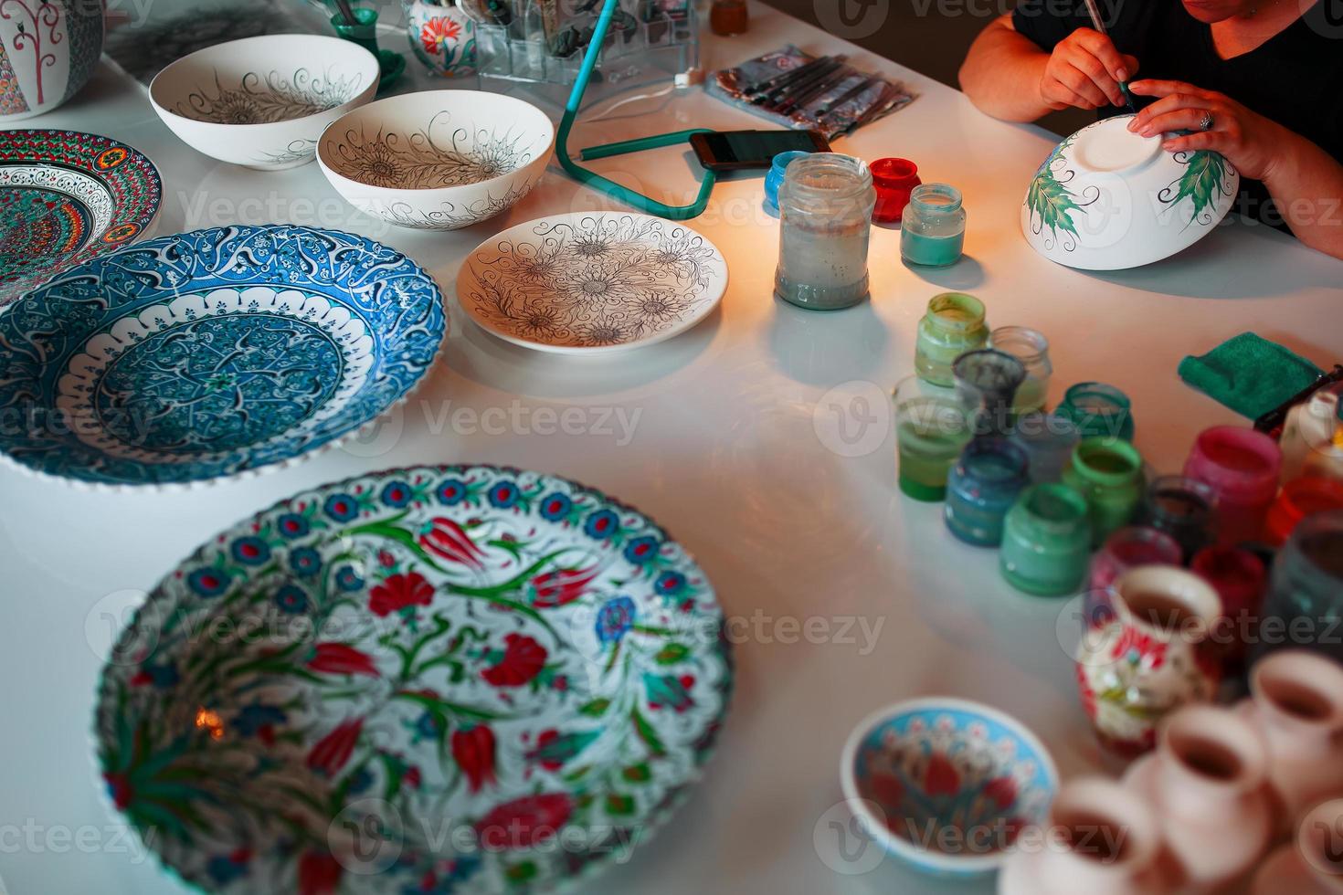 Painting porcelain plates with the hands of a professional craftsman. photo