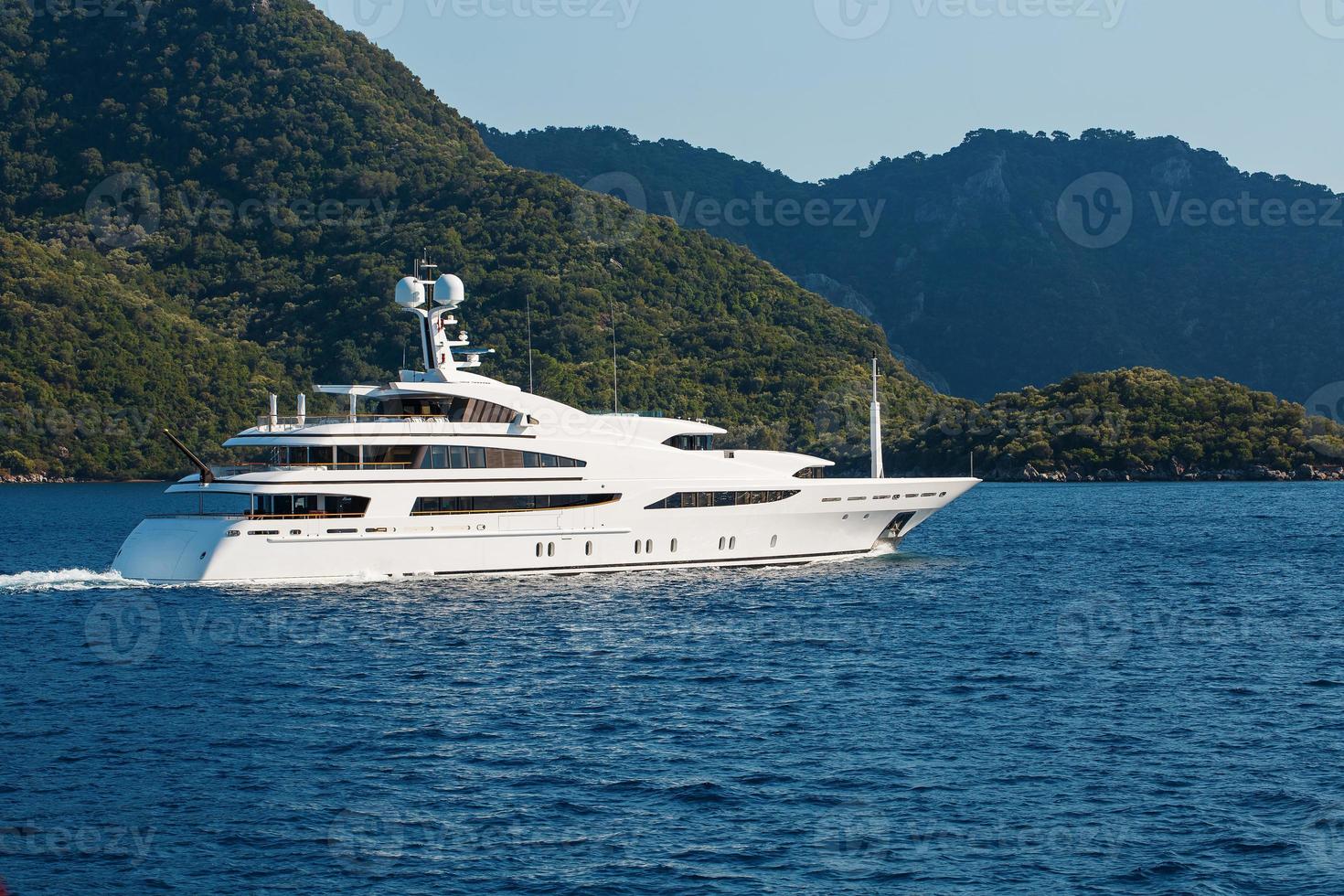 Beautiful modern white yacht with sail on the blue sea, against the backdrop of the mountains. photo