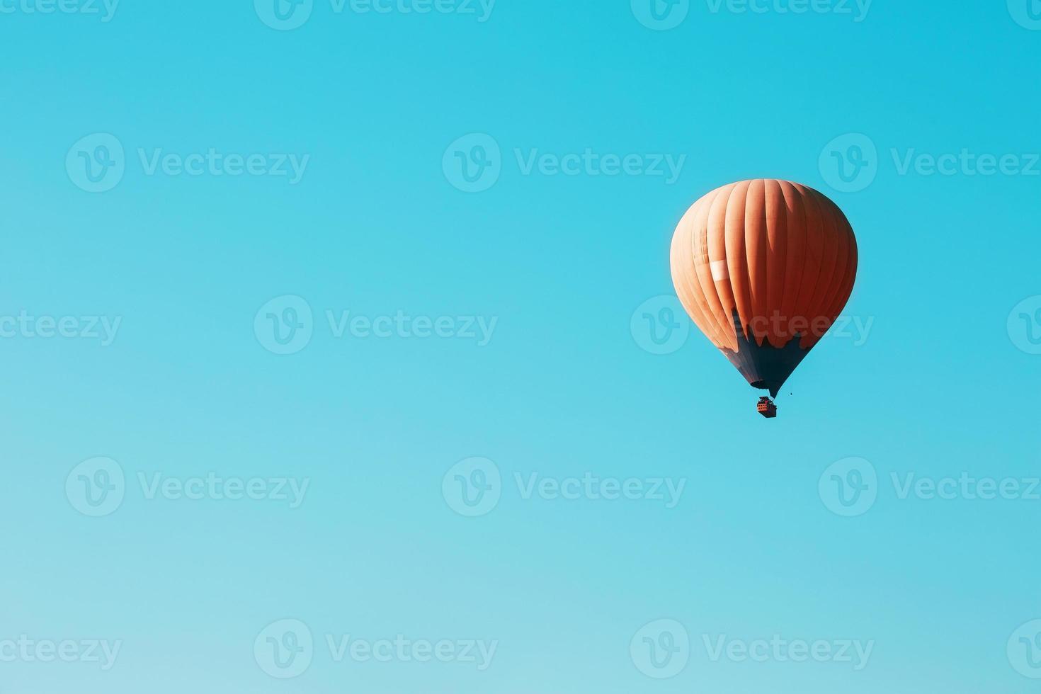 Orange balloon soars against the blue sky photo