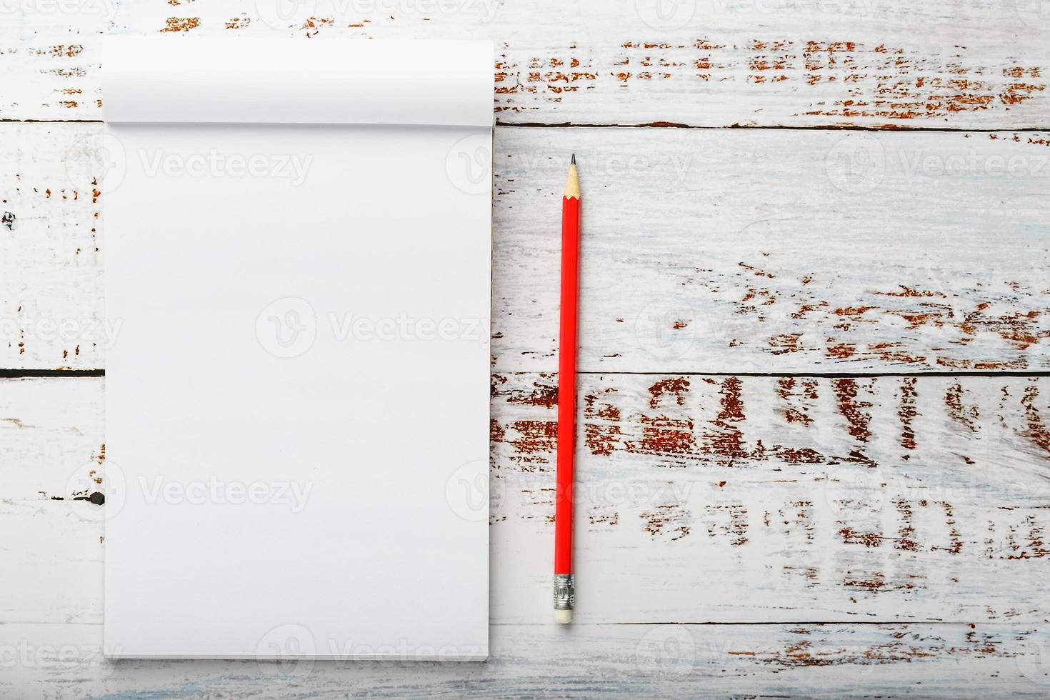 Notepad with a red pencil on a white wooden table against the background, for education, recording goals and deeds photo