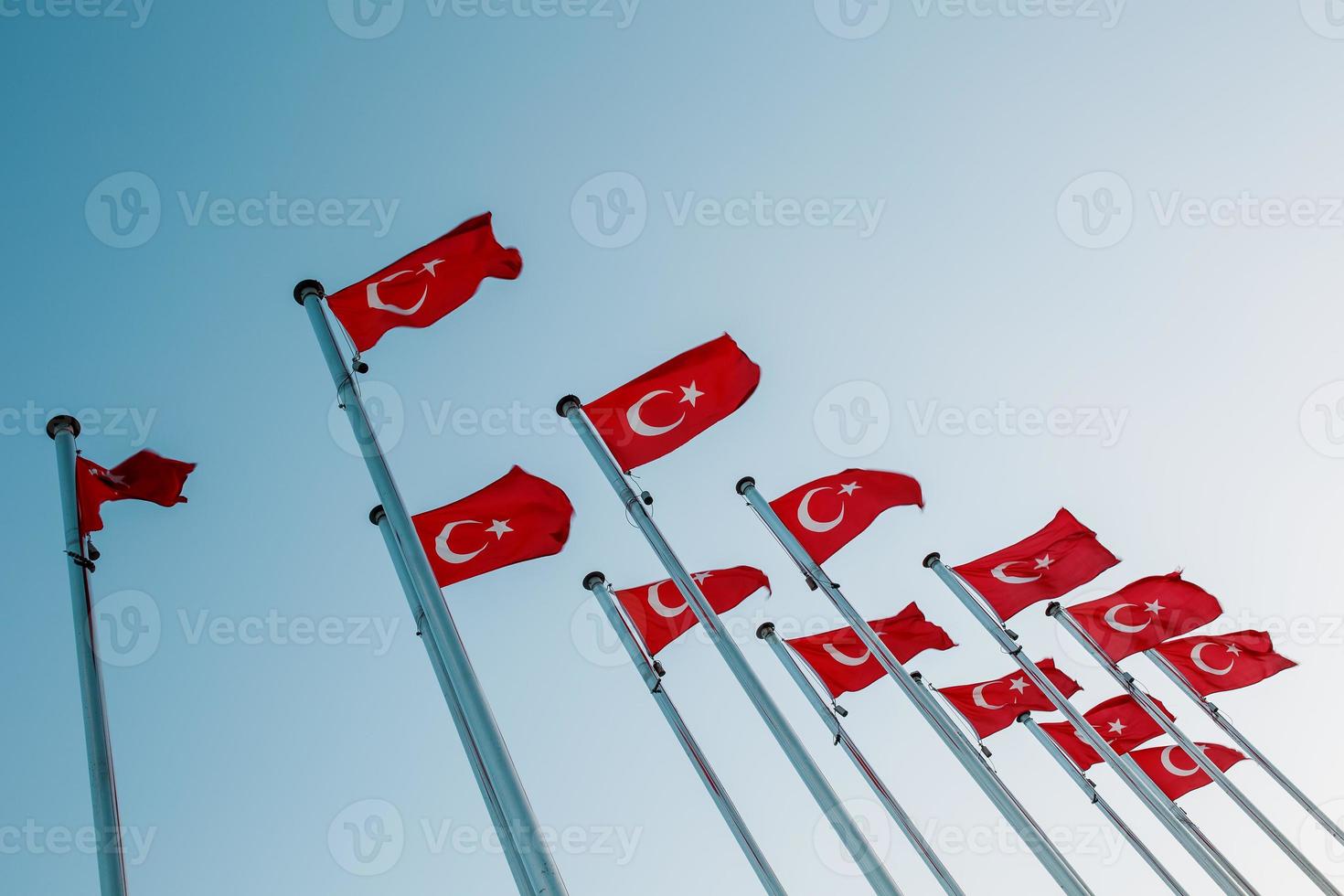 Many national Turkish Flags on the masts against the blue sky. photo