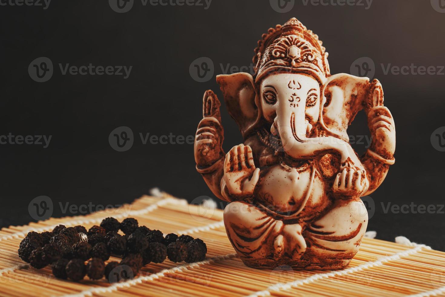 Hindu god Ganesh on a black background. Statue with incense smoke ...