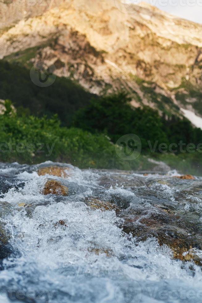 Texture of pure mountain stream against the background of mountains photo