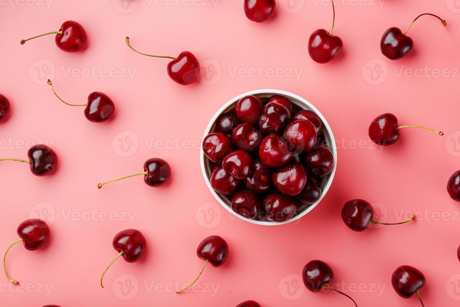 baya de cereza sobre un fondo rosa en una taza blanca, vista superior. foto