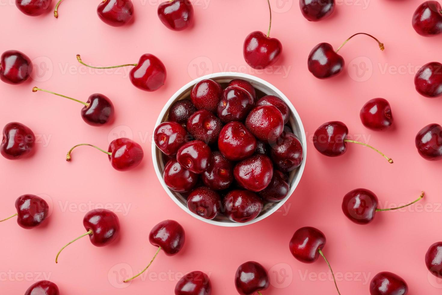 Cherry berry on a pink background in a white cup, top view. photo