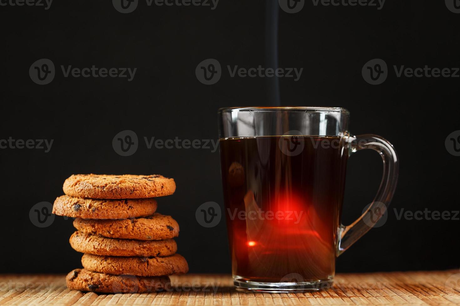 Oatmeal cookies with pieces of chocolate and a mug of coffee on a bamboo stand. photo