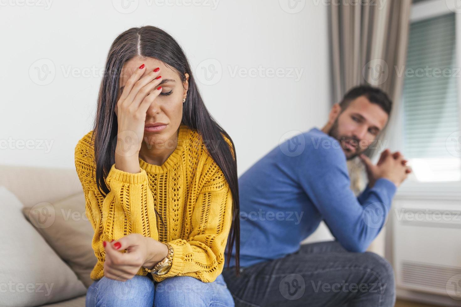 Sad pensive young girl thinking of relationships problems sitting on sofa with offended boyfriend, conflicts in marriage, upset couple after fight dispute, making decision of breaking up get divorced photo