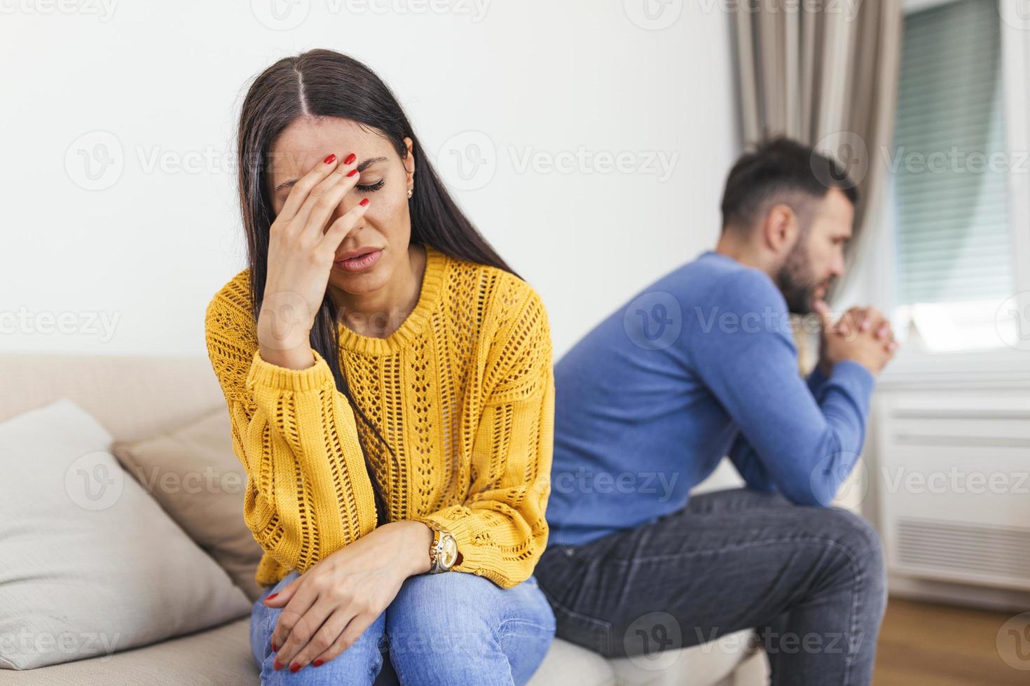 Married couple sitting together not looking at each other on couch in living room at home after quarrel. Angry husband frustrated wife. Break up, problems trouble in relationship concept photo