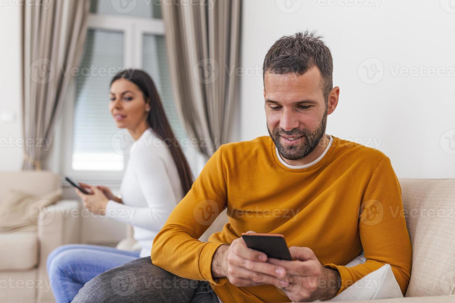 Wife turned her back to husband, reading message on phone from her lover, Man playing games on mobile phone. Cheating and infidelity concept photo