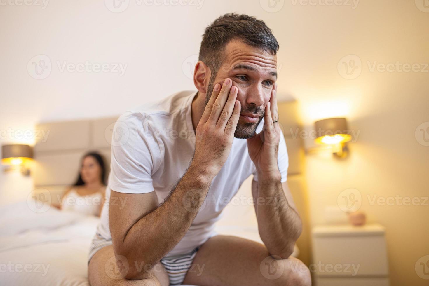 Young couple lying in bed under blanket in bedroom at home, woman in lingerie sleeping, sad, frustrated man thinking about relationships, family having sexual problems, impotence concept close up photo