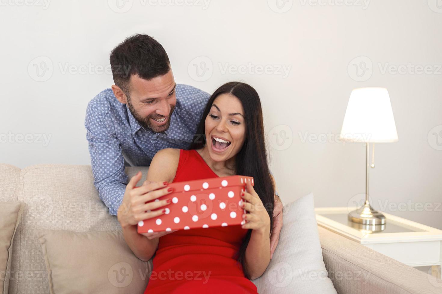 joven pareja enamorada. el hombre sorprende a su mujer con el regalo en el día de san valentín. joven emocionada por el regalo que recibió de su esposo foto