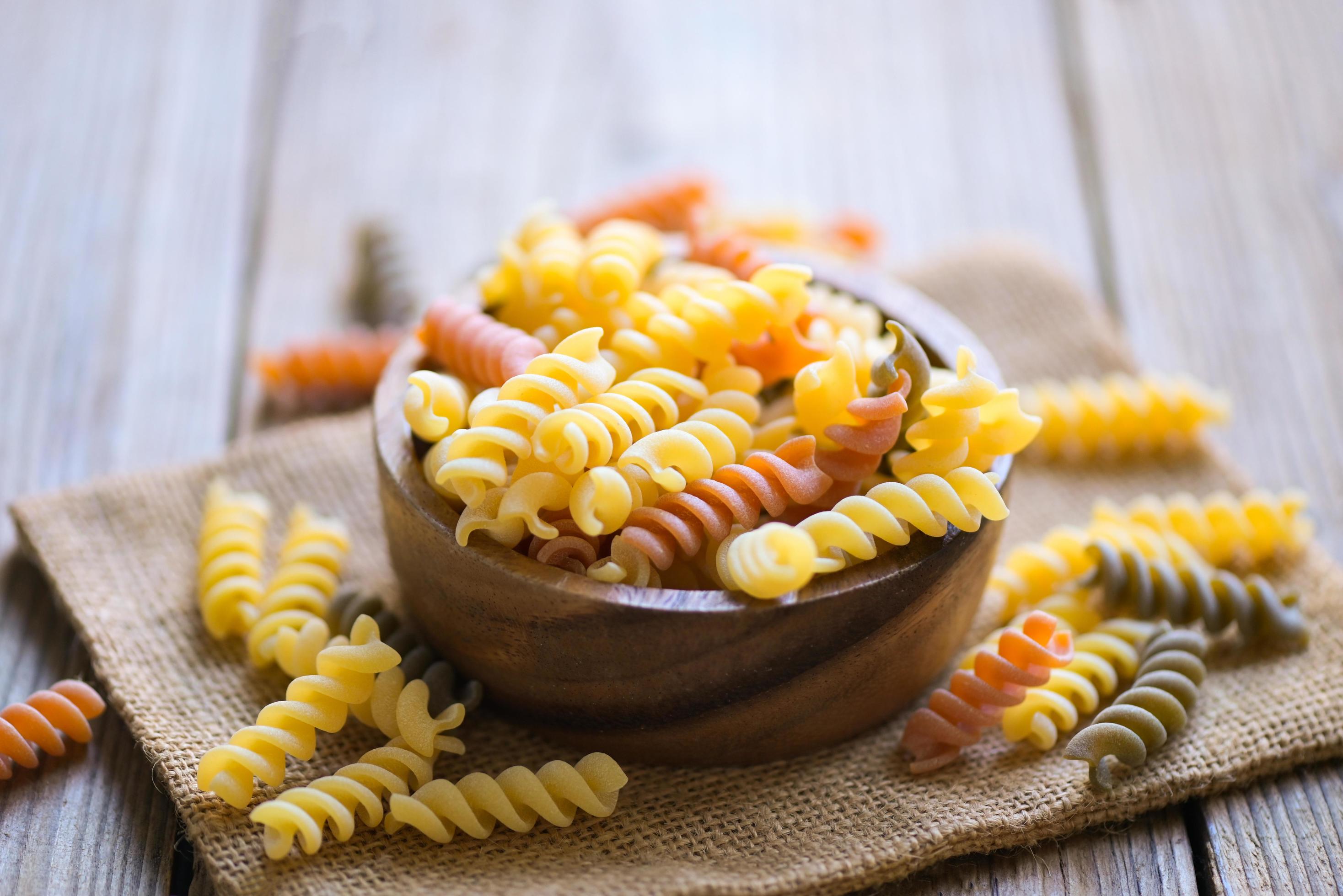 Pasta raw macaroni on wooden bowl background, close up raw macaroni
