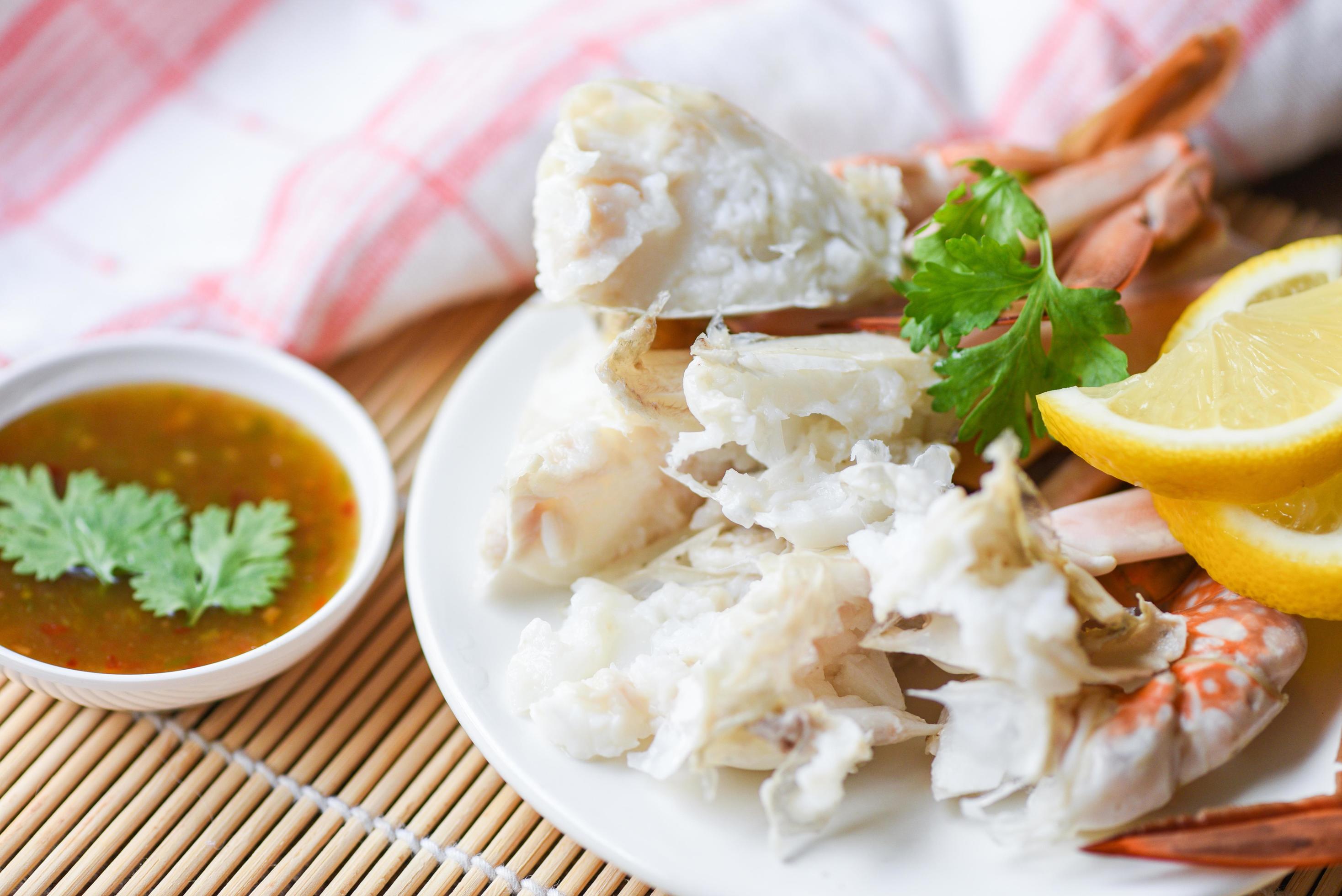 Crab meat - Cooked crab claws and legs on white plate and seafood sauce