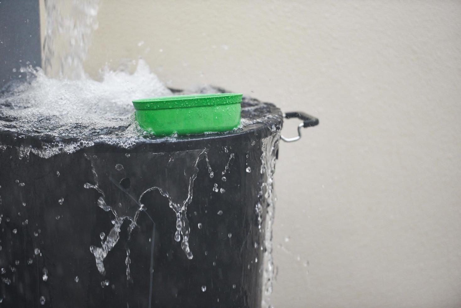 Cubo con salpicaduras de agua cosecha de agua de lluvia en el cubo de agua después de la lluvia foto