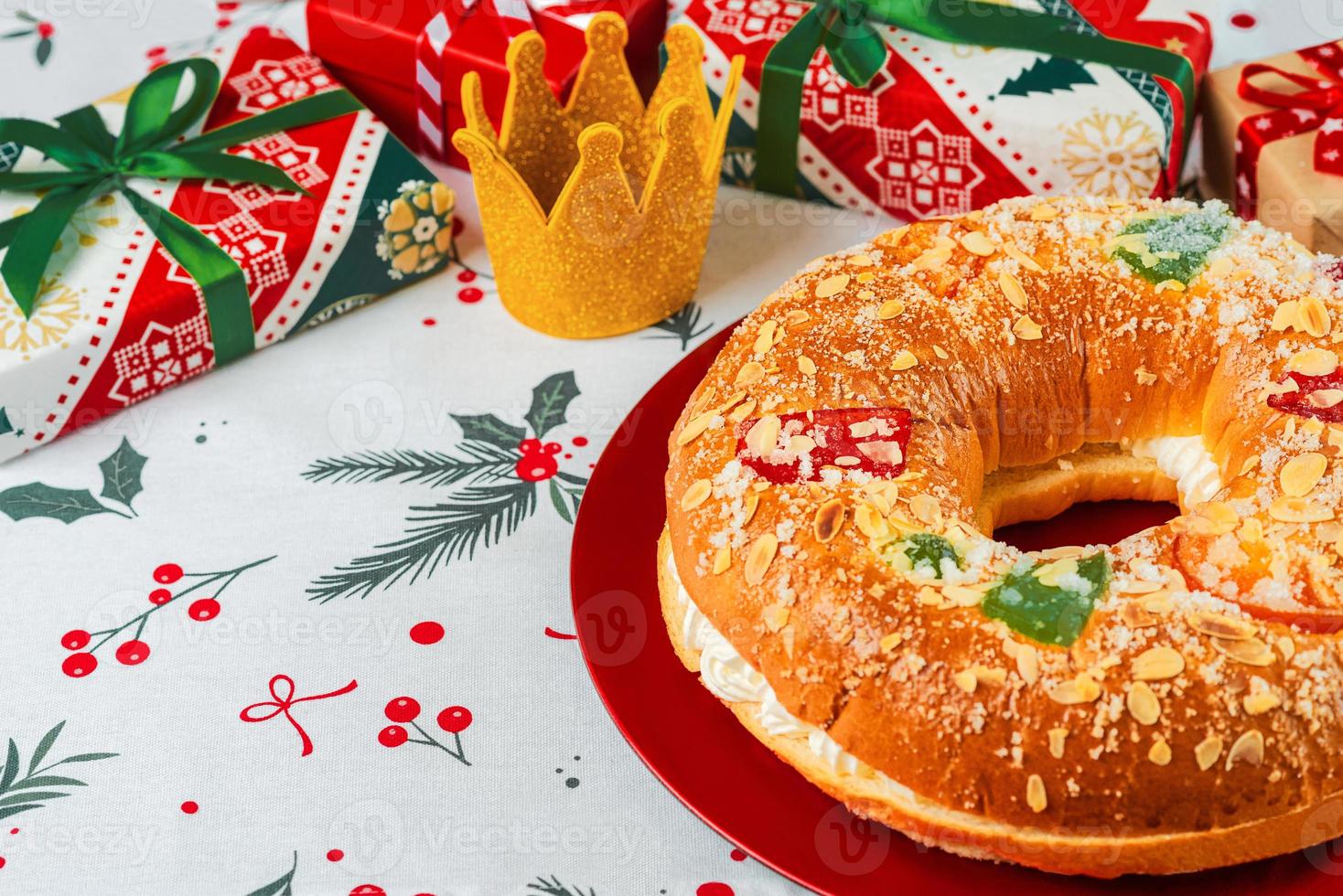 roscon de reyes con crema y adornos navideños en un plato rojo. concepto del día de reyes pastel de reyes magos postre típico español para navidad foto