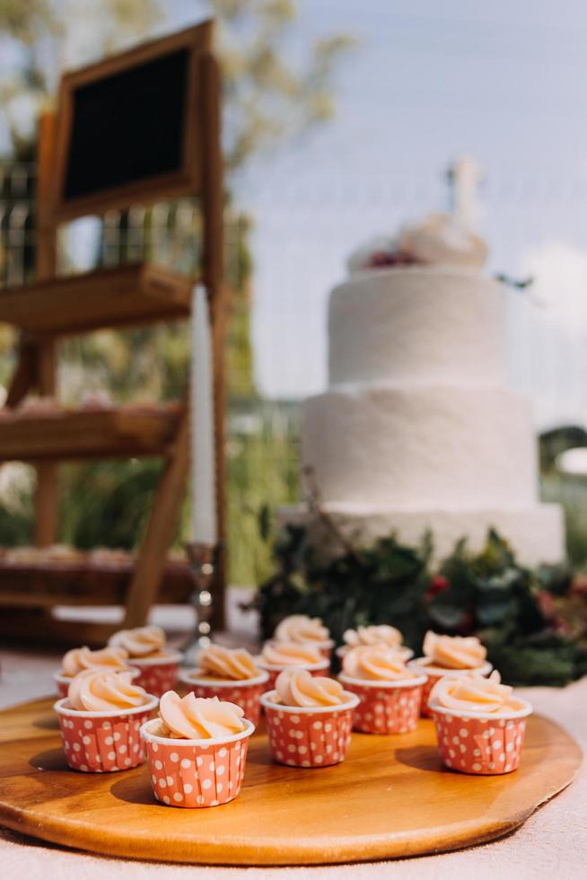 Gourmet cupcakes with white buttercream frosting and sprinkles on wooden background photo