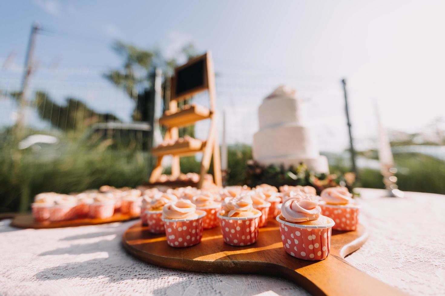 Gourmet cupcakes with white buttercream frosting and sprinkles on wooden background photo