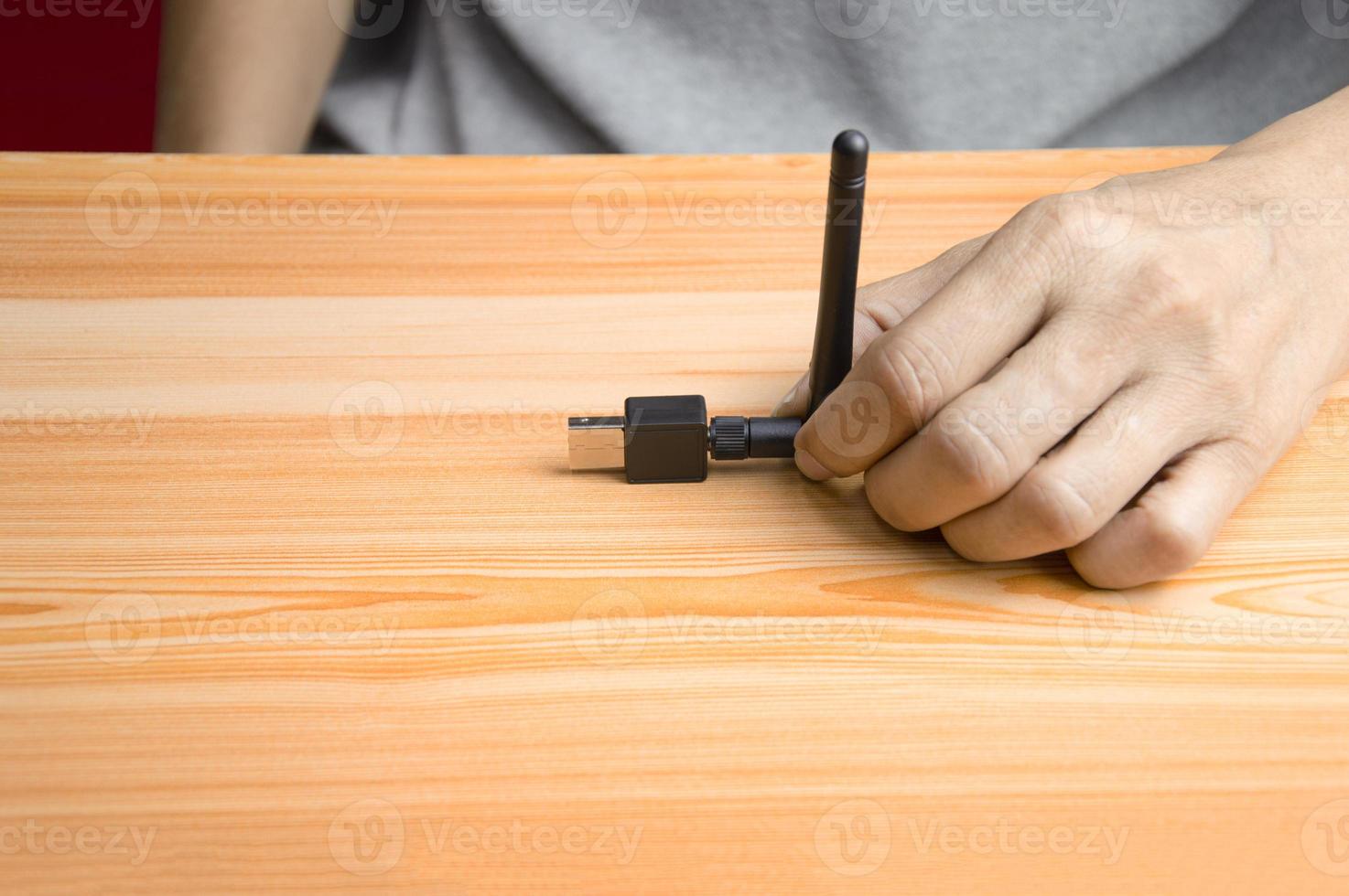 Black usb wifi placed on wooden floor, hand holding usb wifi photo