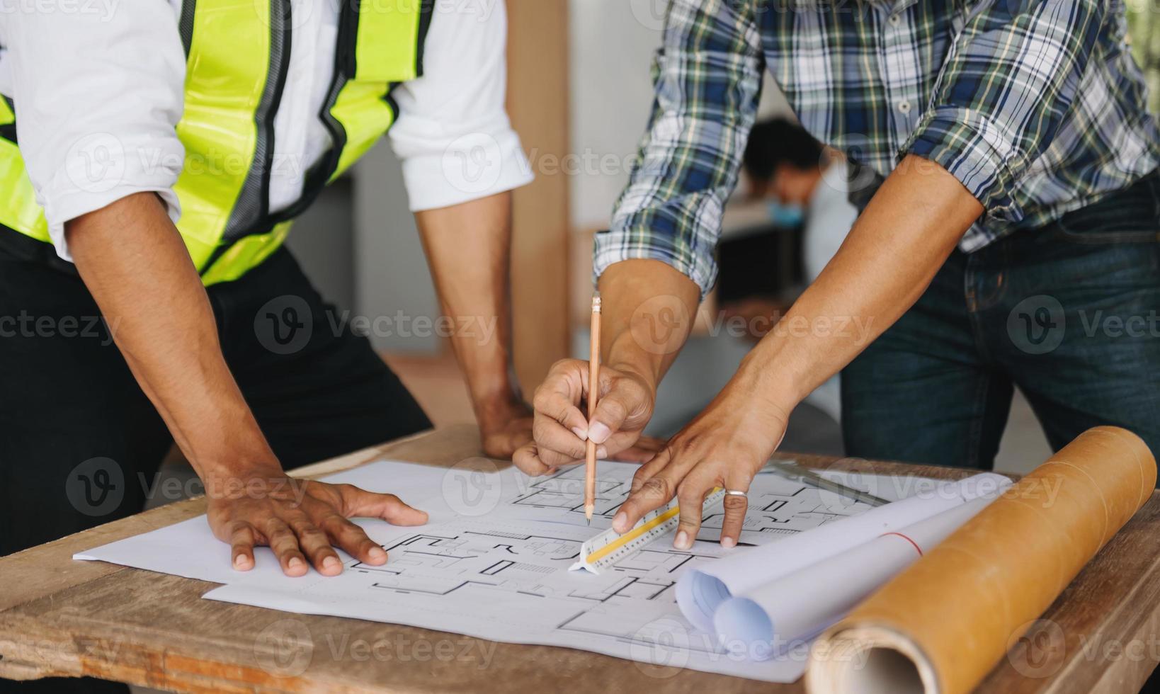 Two colleagues discussing data working and tablet, laptop with on on architectural project at construction site at desk in office photo