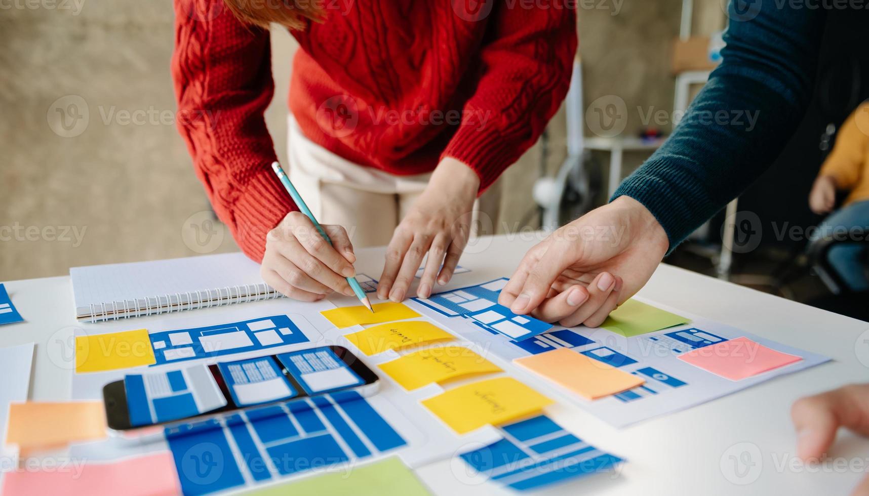 UX developer and ui designer brainstorming about mobile app interface wireframe design with customer breif and color code at office. photo