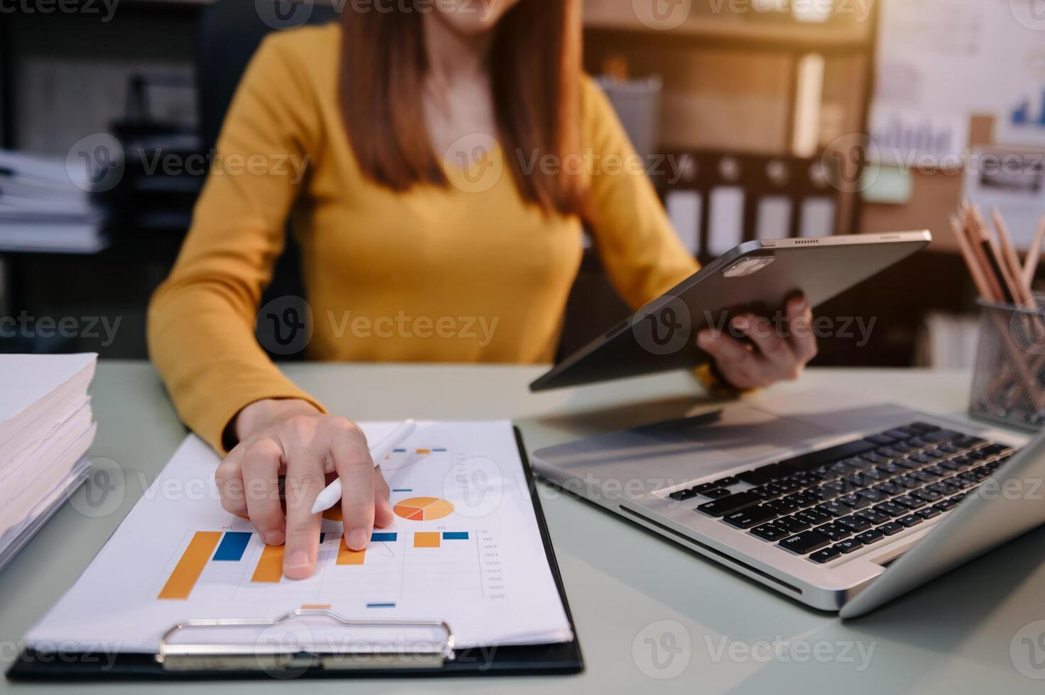 business documents on office table with smart phone and digital tablet and graph financial and woman working photo