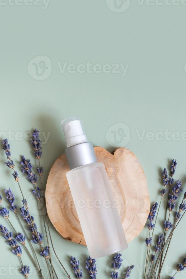 Cosmetic spray bottle on wooden sow top view, flat lay on colored background with lavender flowers. Natural cosmetic concept photo