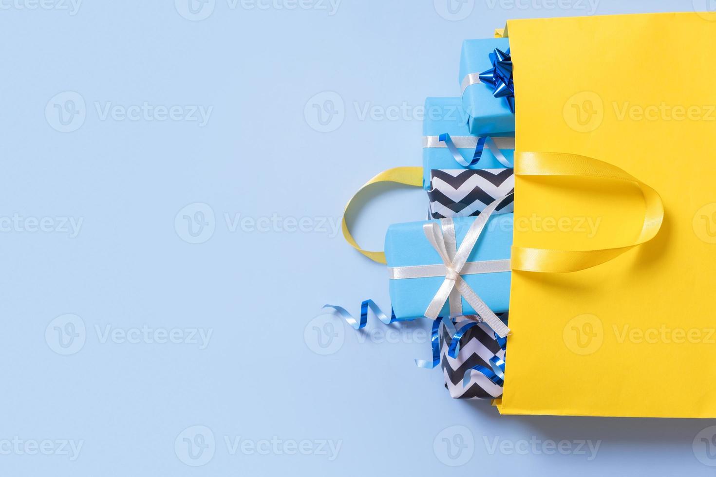 Christmas presents for the holidays concept. Holiday gift boxes with bows in a shopping bag on a color background photo