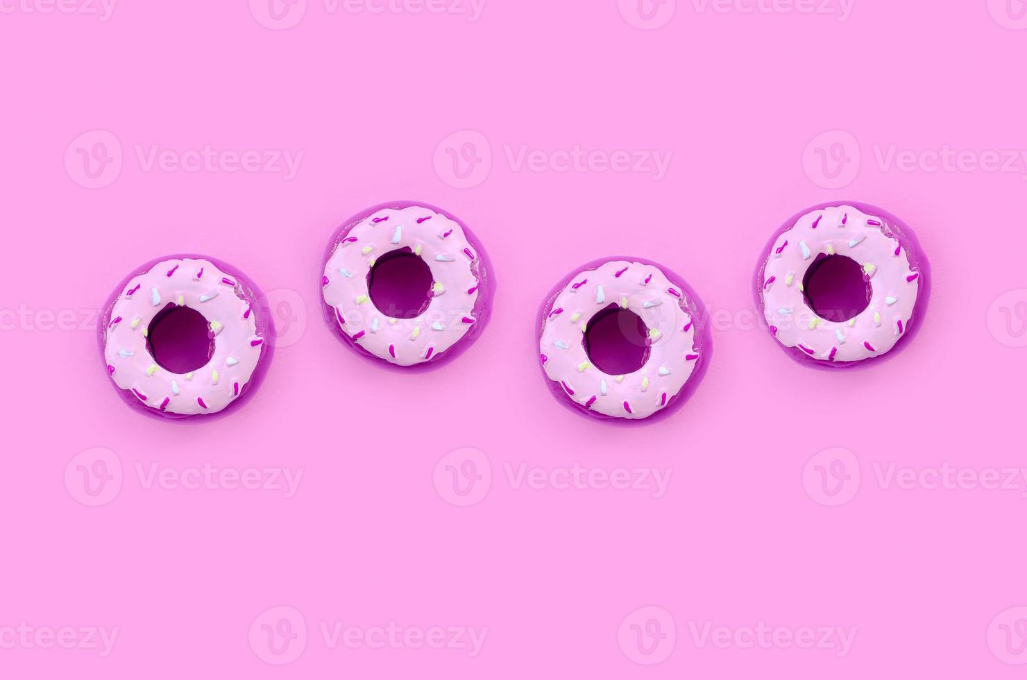 Many small plastic donuts lies on a pastel colorful background. Flat lay minimal pattern. Top view photo