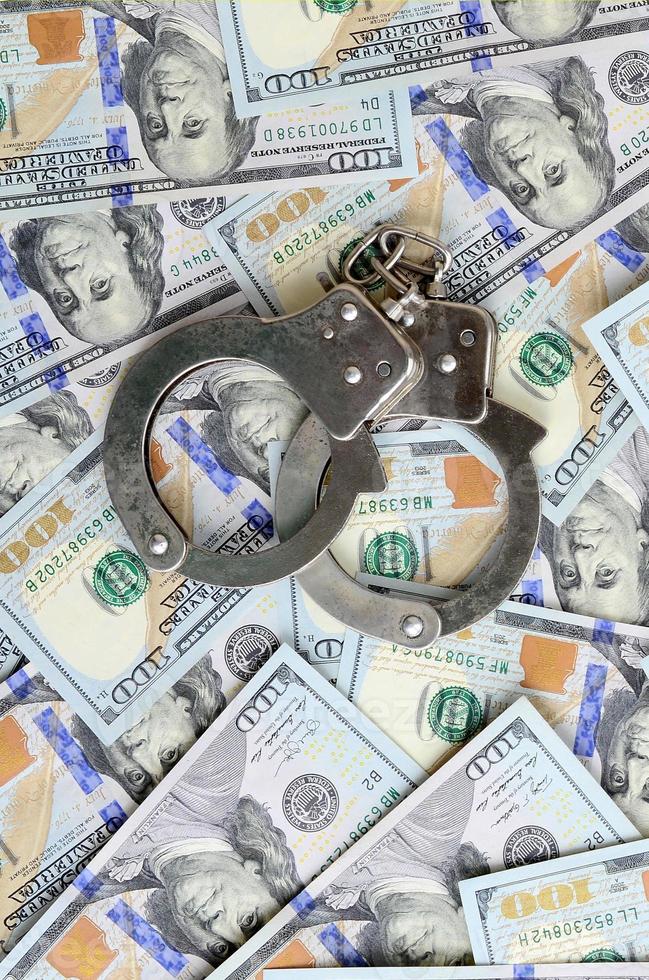 Silver police handcuffs lies on a many dollar bills photo