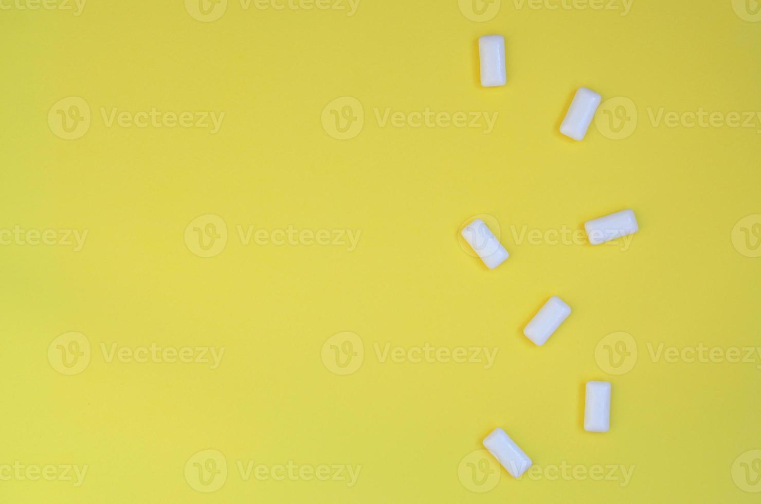 A few chewing gums lie on texture background of fashion pastel yellow color paper in minimal concept photo