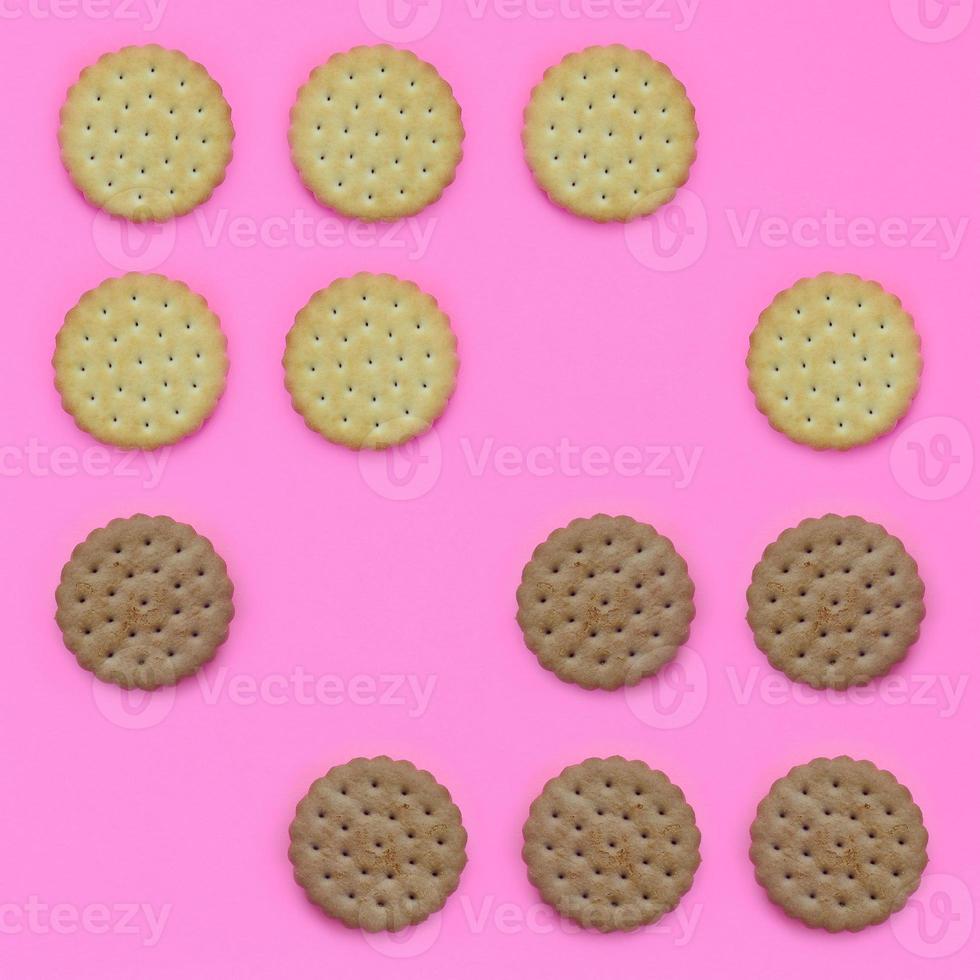 Pattern of a brown biscuits on a pink background. Trendy minimal concept of food and dessert. Abstract flat lay, top view photo