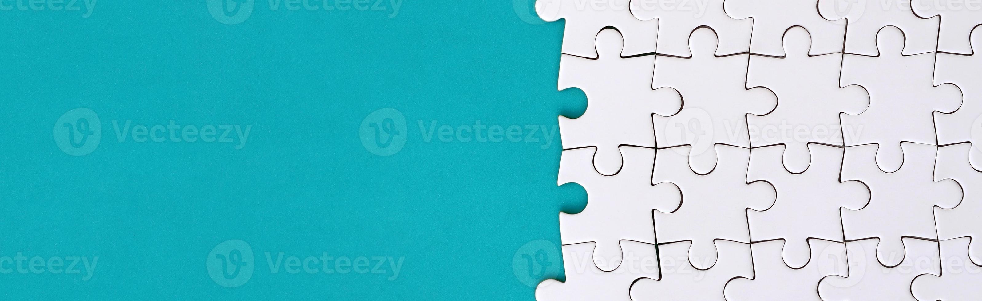 Fragment of a folded white jigsaw puzzle on the background of a blue plastic surface. Texture photo with copy space for text