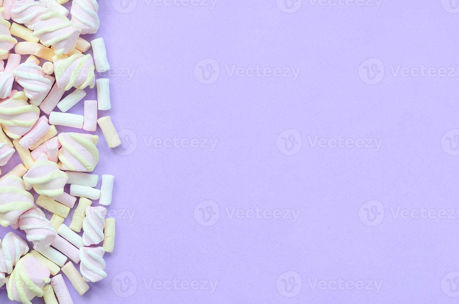 Colorful marshmallow laid out on violet paper background. pastel creative texture. minimal photo