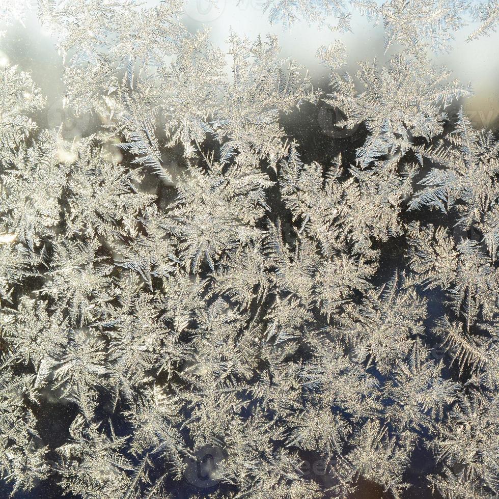 Snowflakes frost rime macro on window glass pane photo