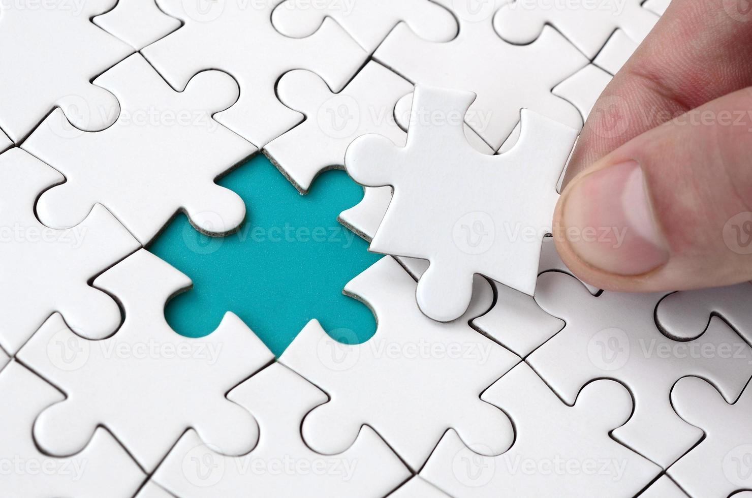 The human hand fills the last missing elements of the surface from the jigsaw puzzle. The concept of the completion of the initiated cases photo