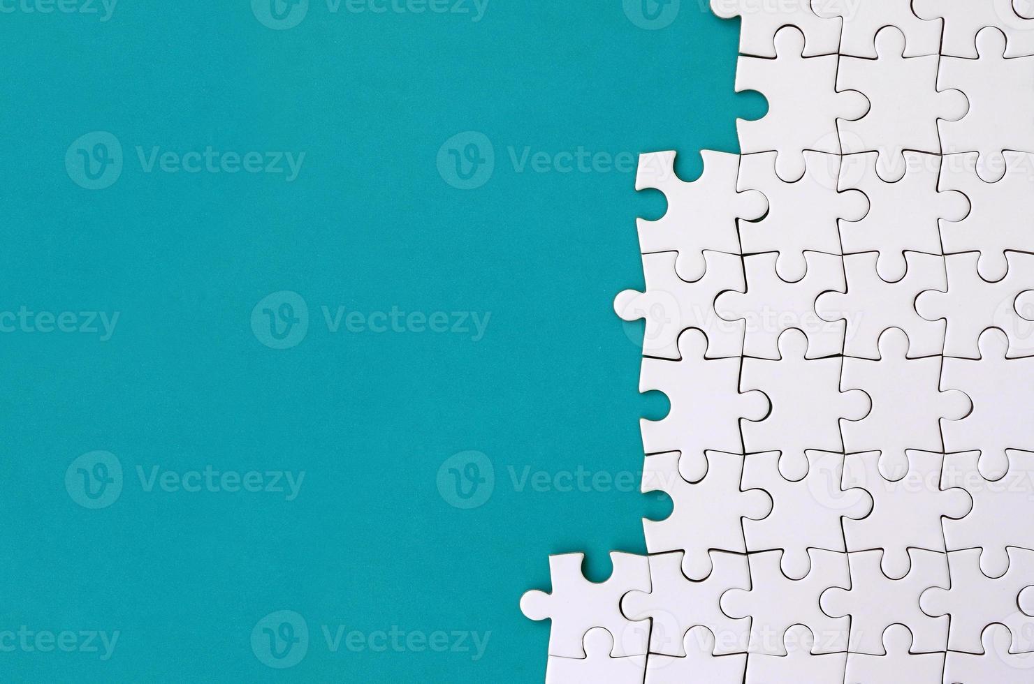 Fragment of a folded white jigsaw puzzle on the background of a blue plastic surface. Texture photo with copy space for text