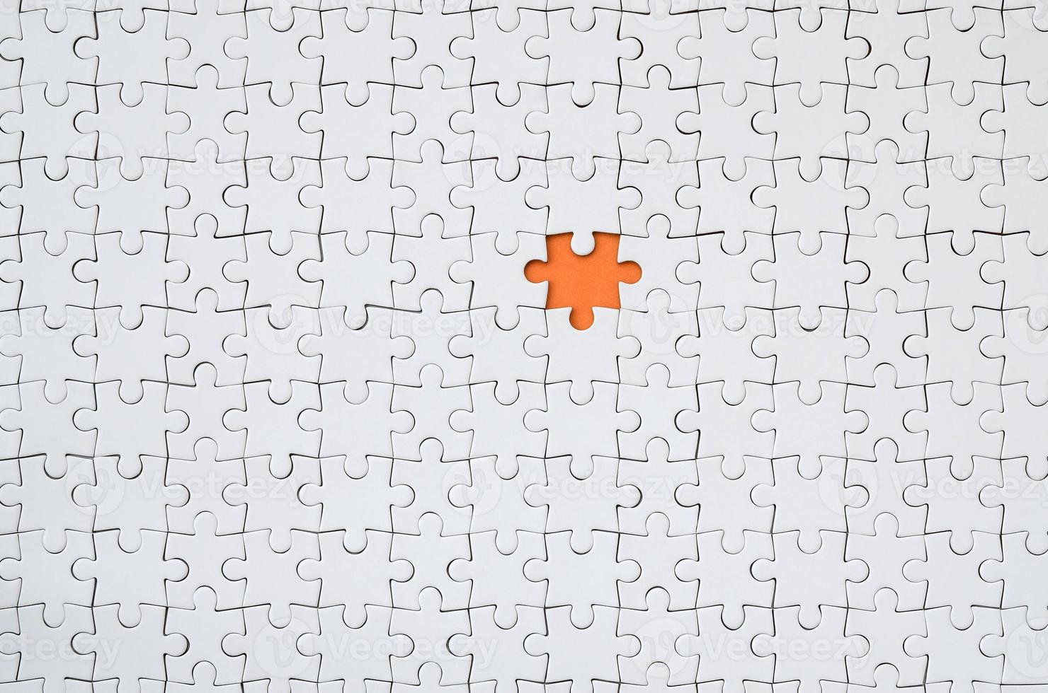 la textura de un rompecabezas blanco en un estado ensamblado con un elemento que falta formando un espacio naranja foto