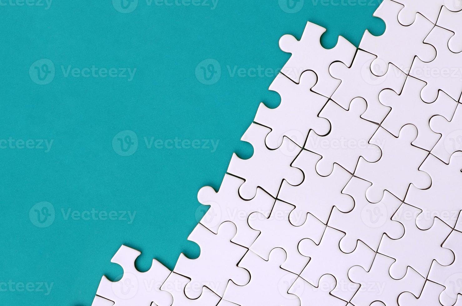 Fragment of a folded white jigsaw puzzle on the background of a blue plastic surface. Texture photo with copy space for text