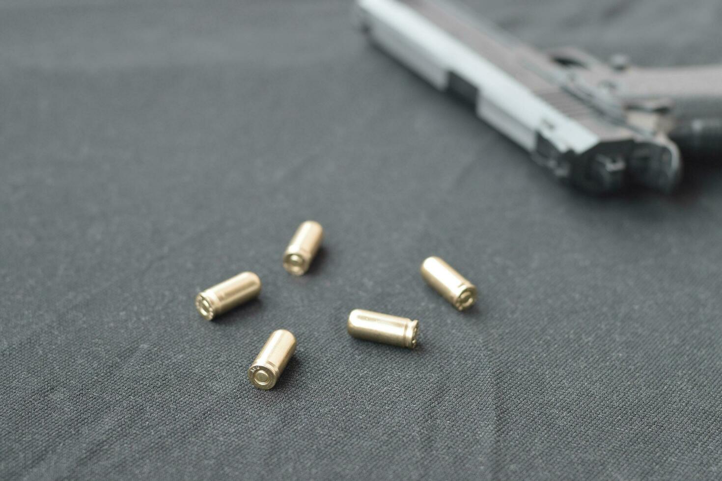 9mm bullets and pistol lie on a black fabric. A set shooting range items or a self-defense kit photo