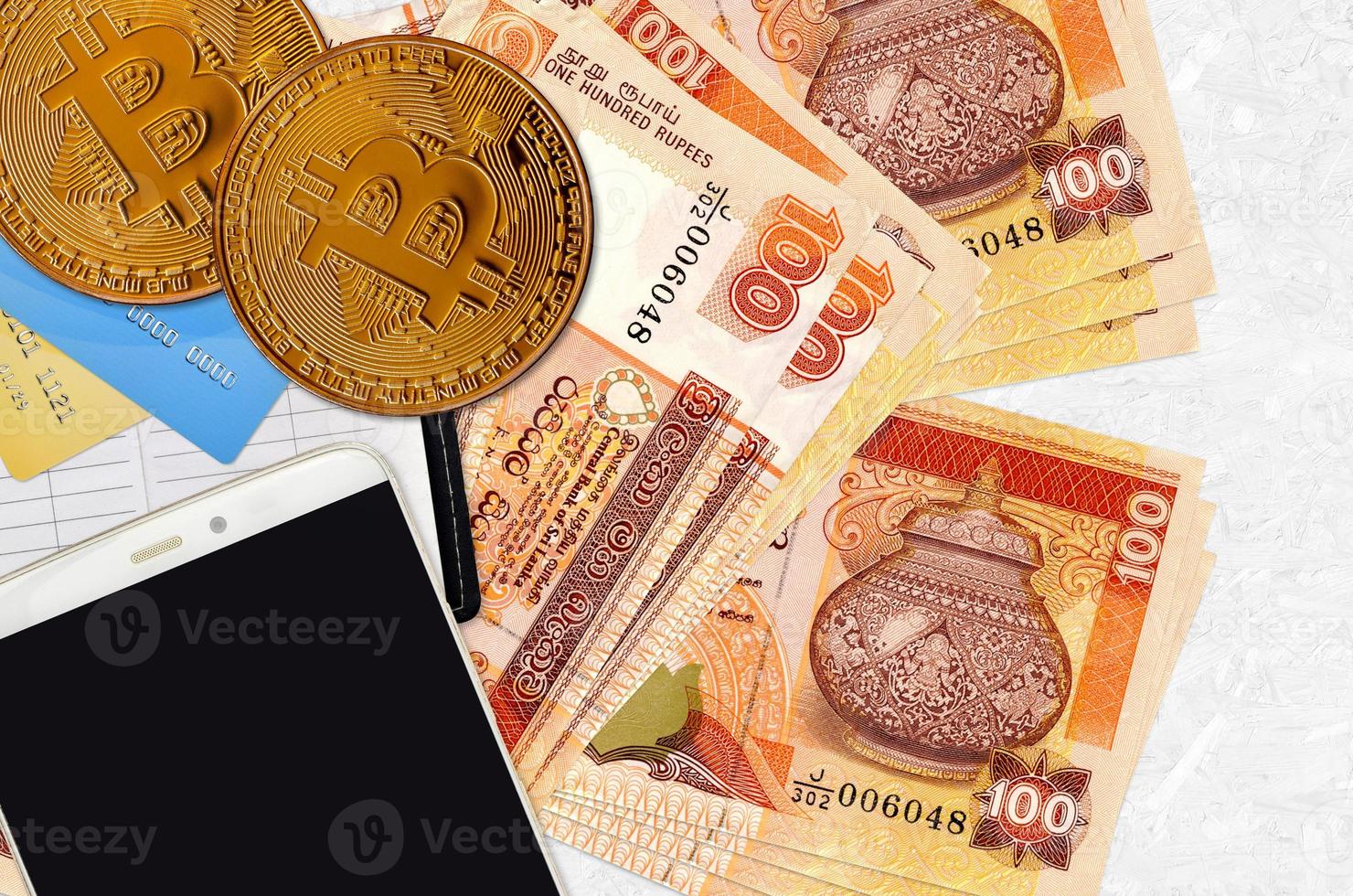 100 Sri Lankan rupees bills and golden bitcoins with smartphone and