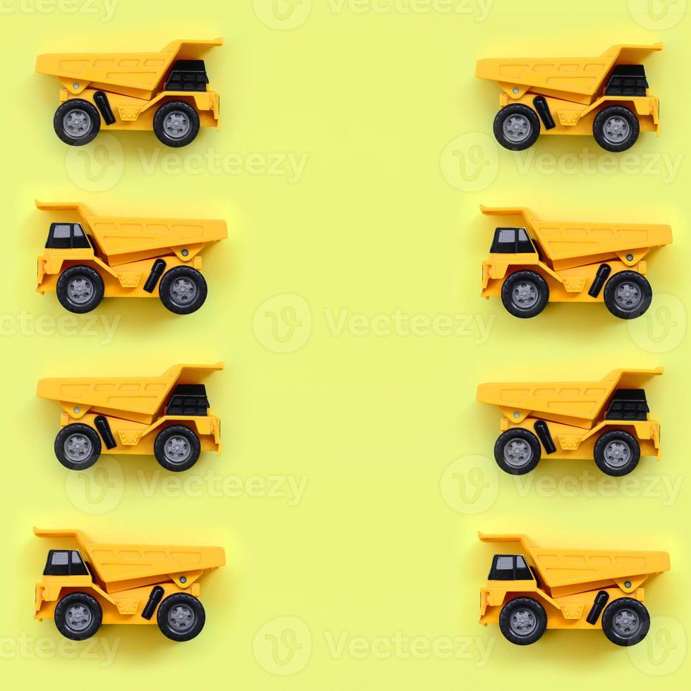 Many small yellow toy trucks on texture background of fashion pastel yellow color paper in minimal concept photo