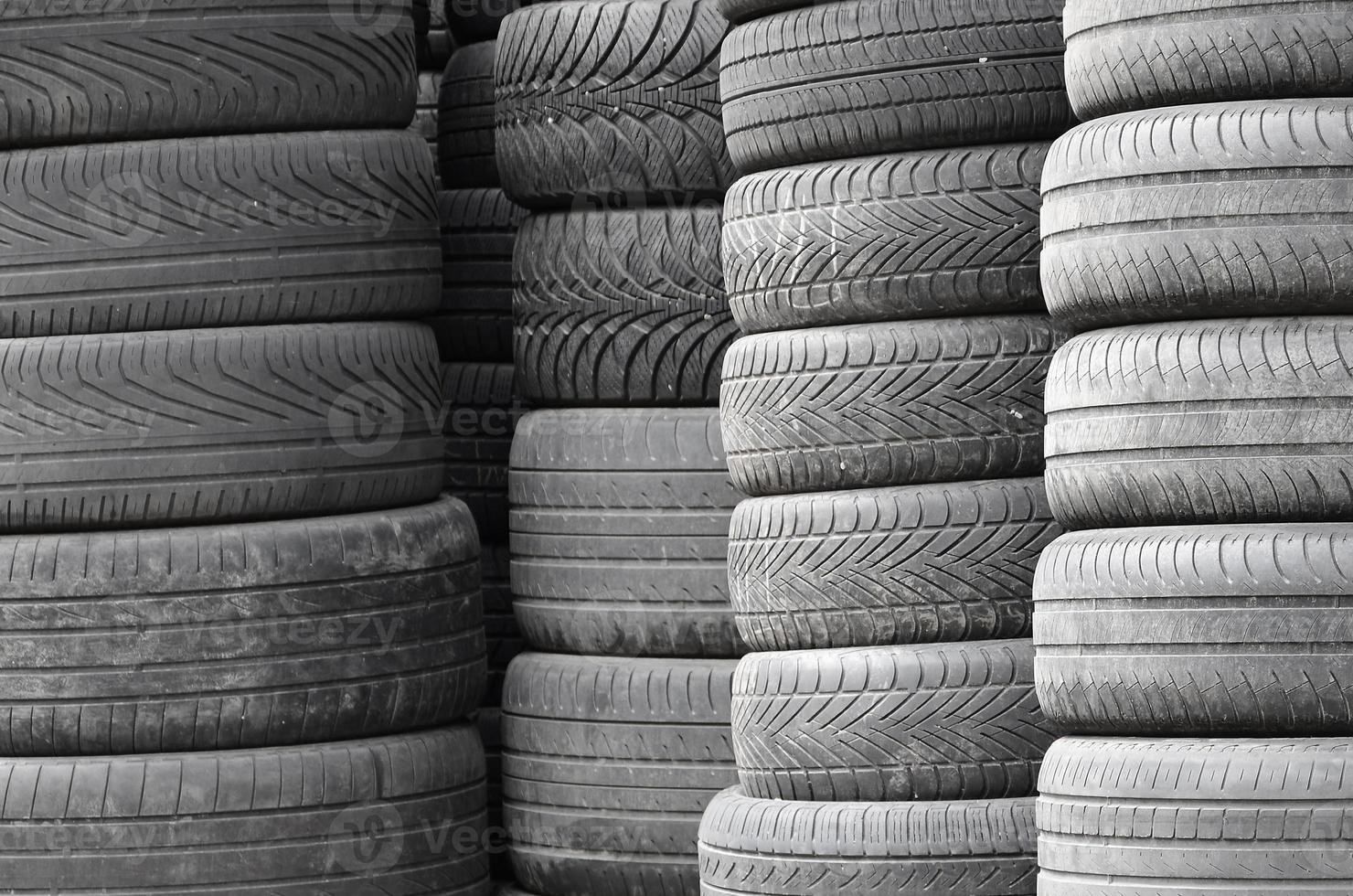 Old used tires stacked with high piles in secondary car parts shop garage photo
