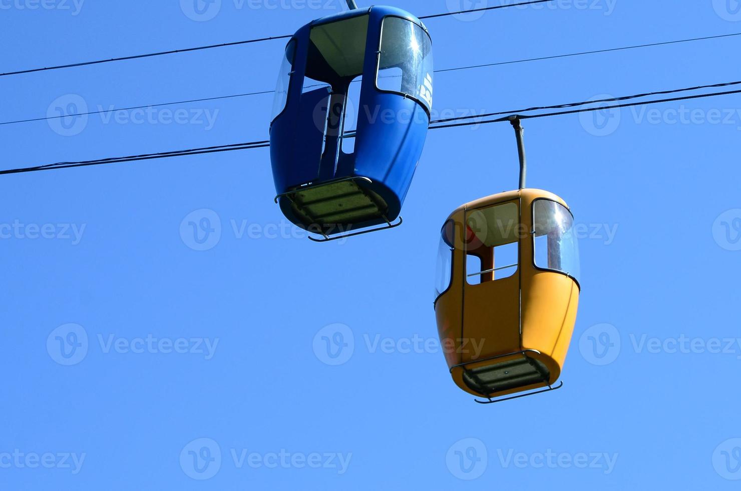 Blue and yellow passenger cable way cabins in the clear sky photo