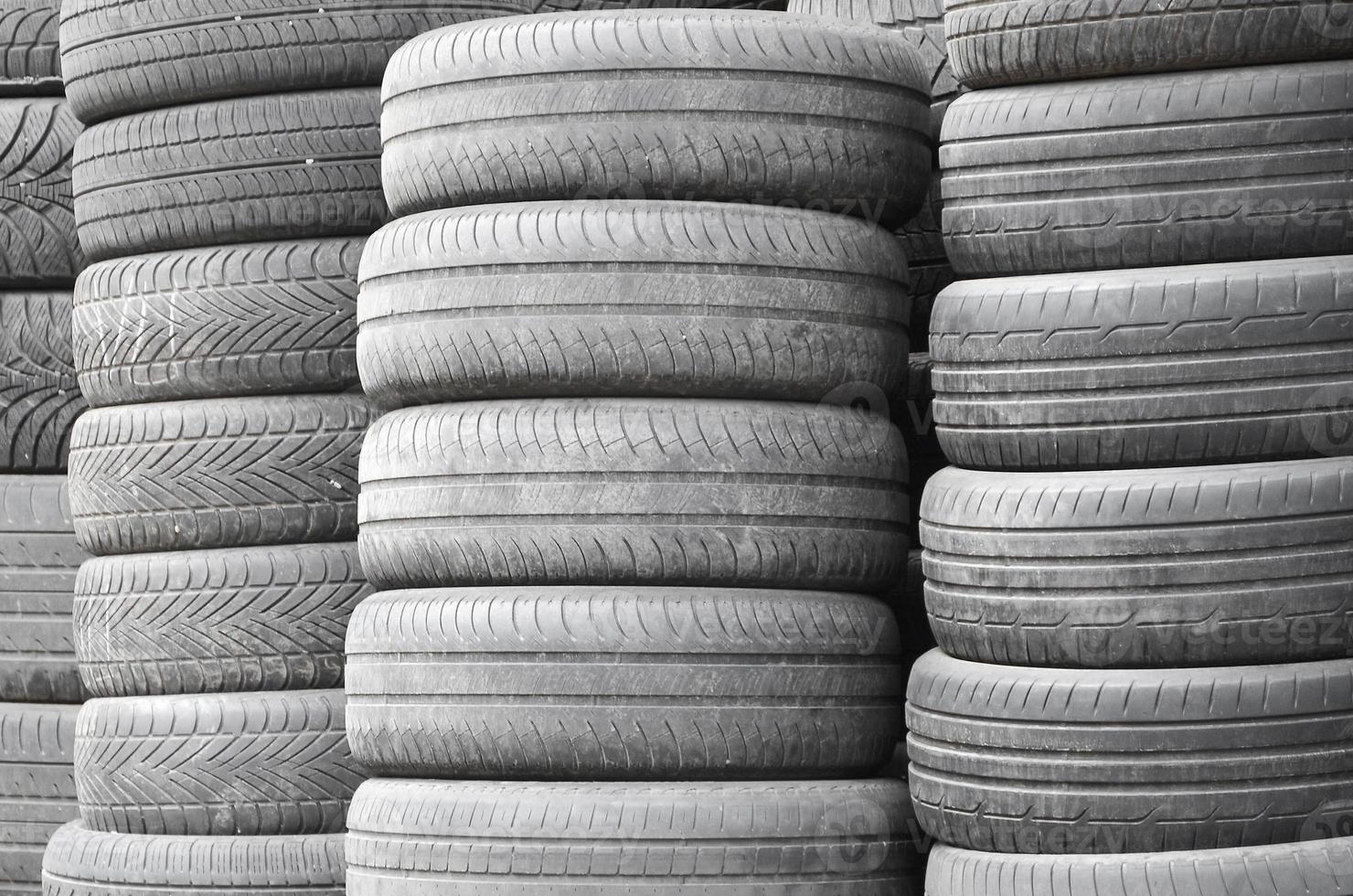 Old used tires stacked with high piles in secondary car parts shop garage photo