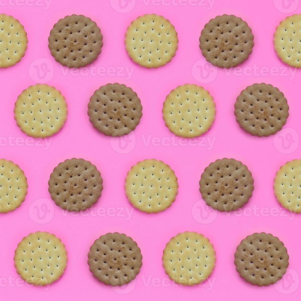 Pattern of a brown biscuits on a pink background. Trendy minimal concept of food and dessert. Abstract flat lay, top view photo