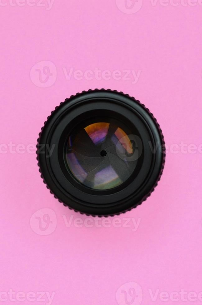 Camera lens with a closed aperture lie on texture background of fashion pastel pink color paper in minimal concept photo