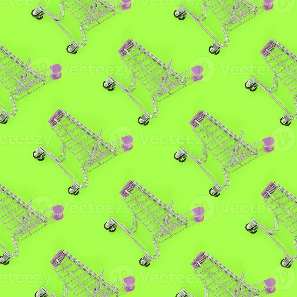 Shopping addiction, shopping lover or shopaholic concept. Many small empty shopping carts perform a pattern on a pastel colored paper background. Flat lay composition, top view photo